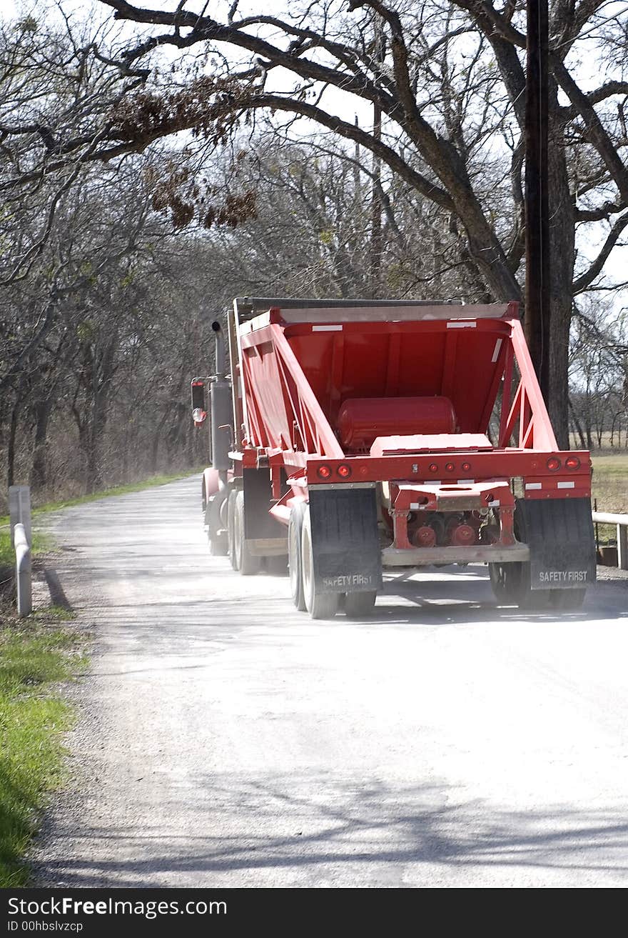 A Rear View of Red Eighteen Wheel Truck going down country road. A Rear View of Red Eighteen Wheel Truck going down country road.