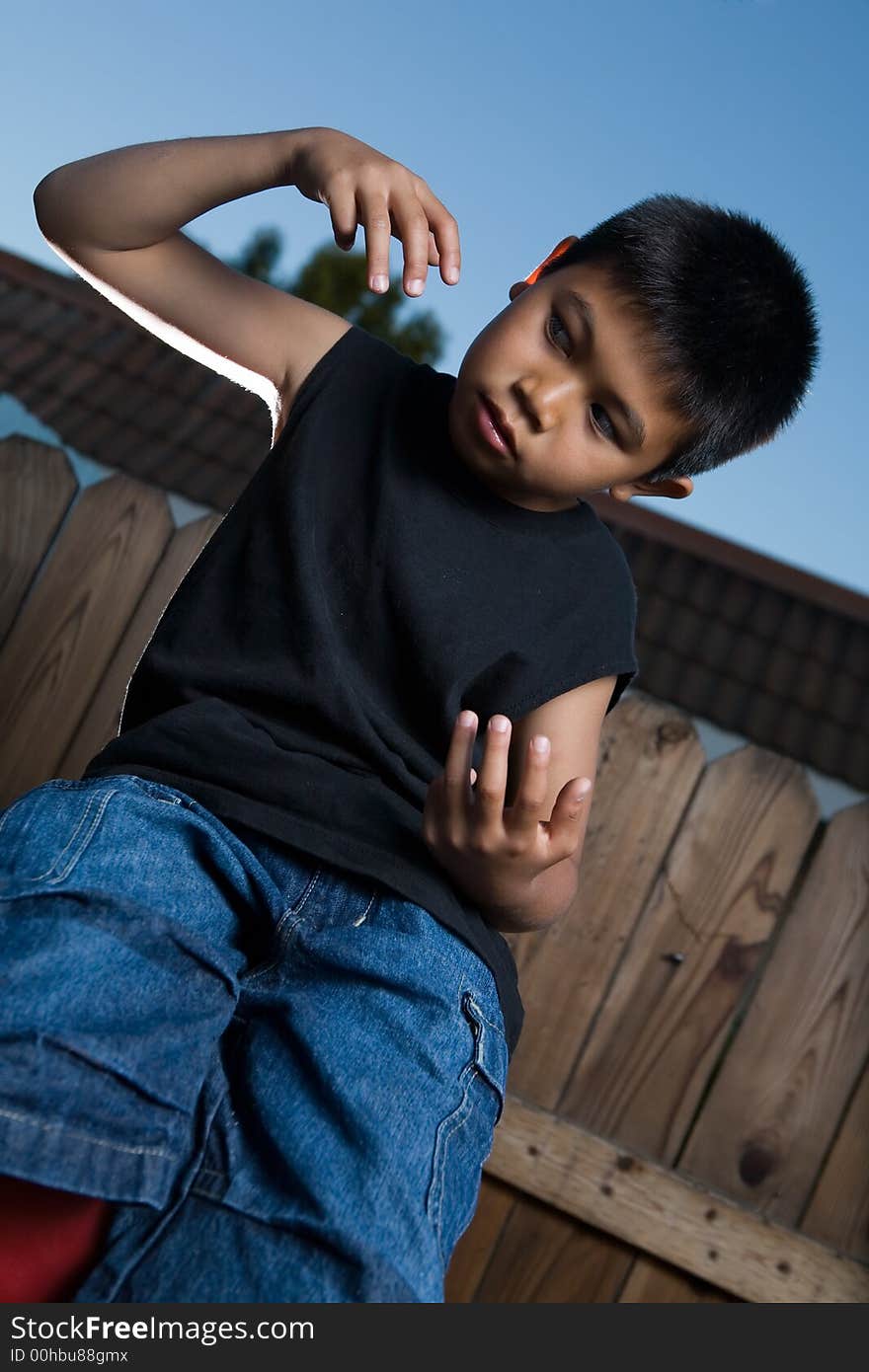 Young asian boy outside beside a tall wooden fence wearing jeans and black tshirt. Young asian boy outside beside a tall wooden fence wearing jeans and black tshirt