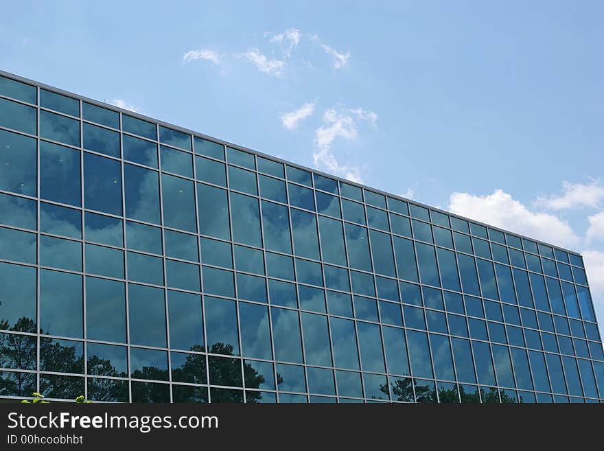 Blue glass office building reflecting the sky with clouds. Blue glass office building reflecting the sky with clouds