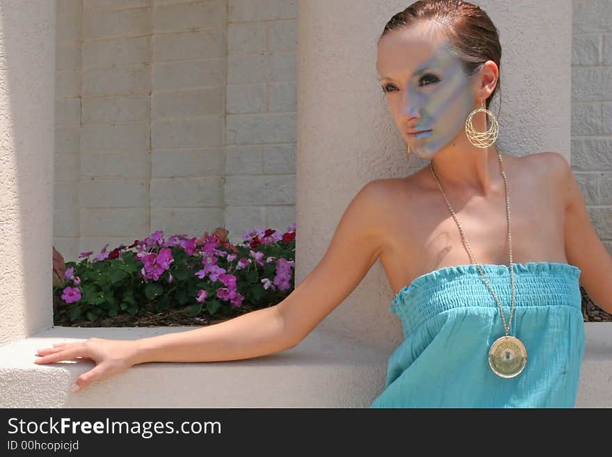 A fashion makeup model leaning against a planter. A fashion makeup model leaning against a planter