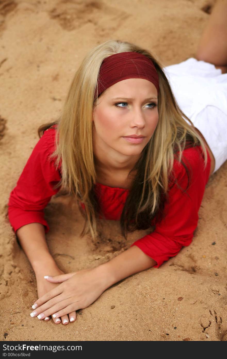 A young beautiful woman lying on a beach is smiling. A young beautiful woman lying on a beach is smiling