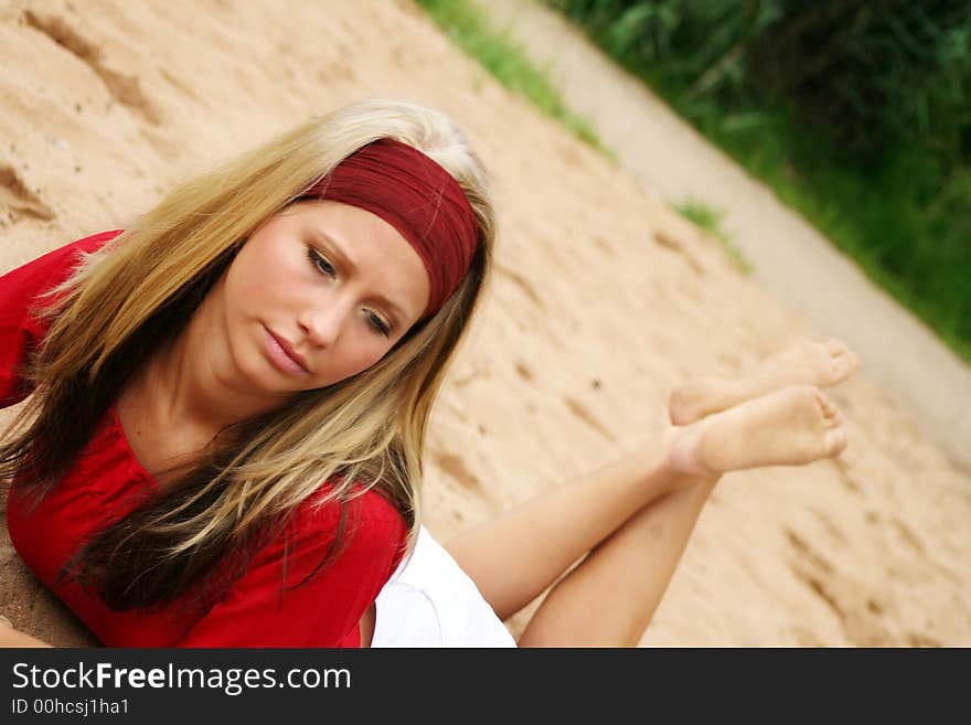 A young beautiful woman lying on a beach is smiling. A young beautiful woman lying on a beach is smiling