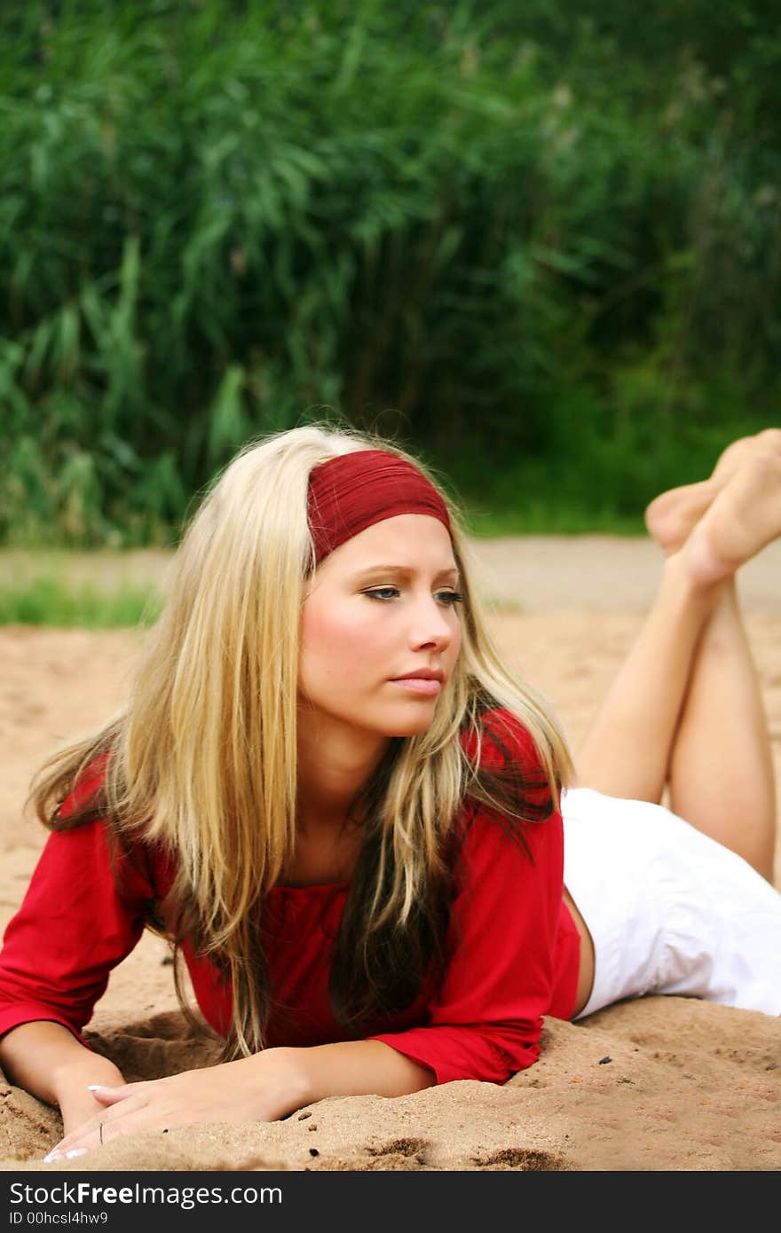 A young beautiful woman lying on a beach is smiling. A young beautiful woman lying on a beach is smiling