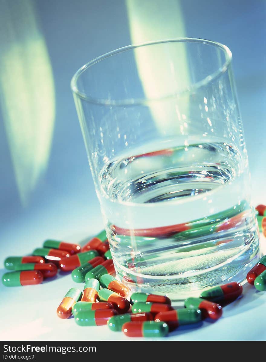 Glass with water and tablets on a blue background . Glass with water and tablets on a blue background