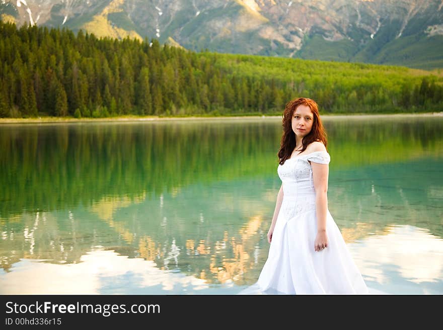 A newly married bride poses for a portrait on the shores of Patricia Lake in Jasper National Park, Canada. A newly married bride poses for a portrait on the shores of Patricia Lake in Jasper National Park, Canada.