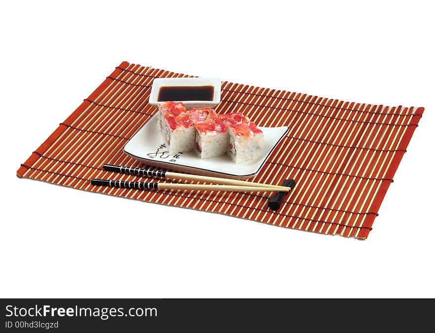 Sushi, soya sauce, chopsticks are located on bamboo mat. Sushi, soya sauce, chopsticks are located on bamboo mat