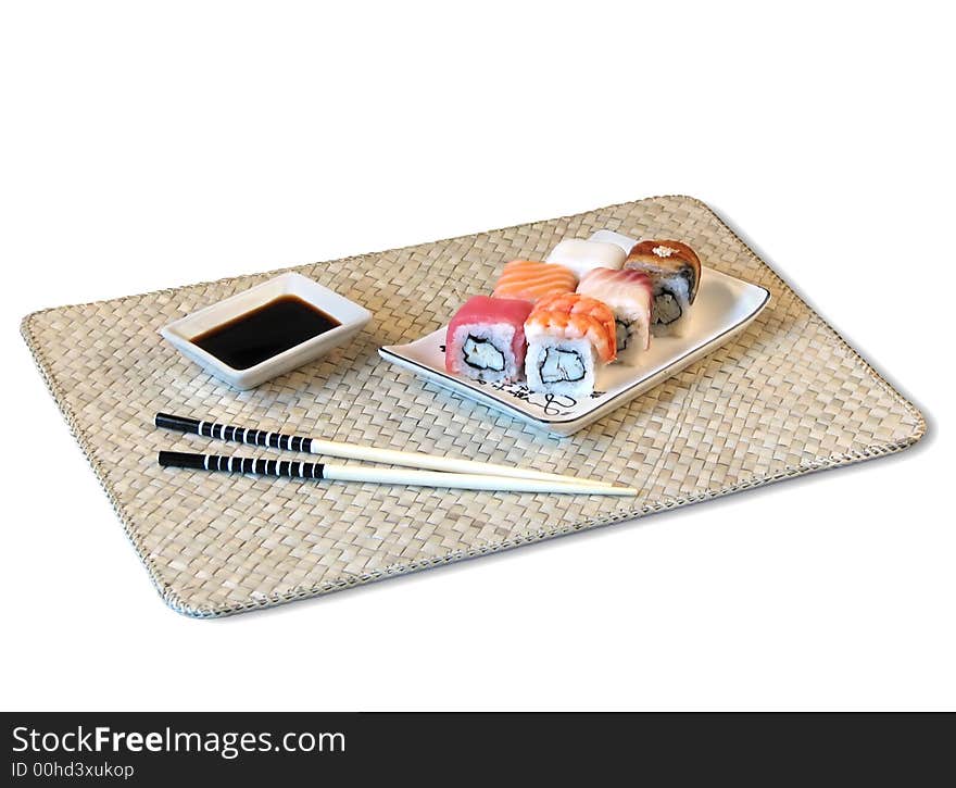 Sushi, soya sauce, chopsticks are located on bamboo mat. Sushi, soya sauce, chopsticks are located on bamboo mat