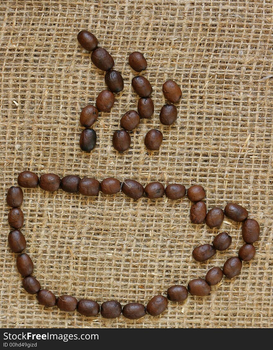 Outline of coffee cup made from coffee beans over burlap background