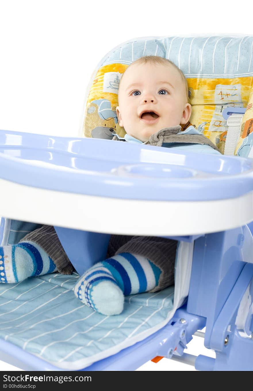 Funny infant smiling and sitting on baby's chair, wearing dungarees. Front view, white background. Funny infant smiling and sitting on baby's chair, wearing dungarees. Front view, white background