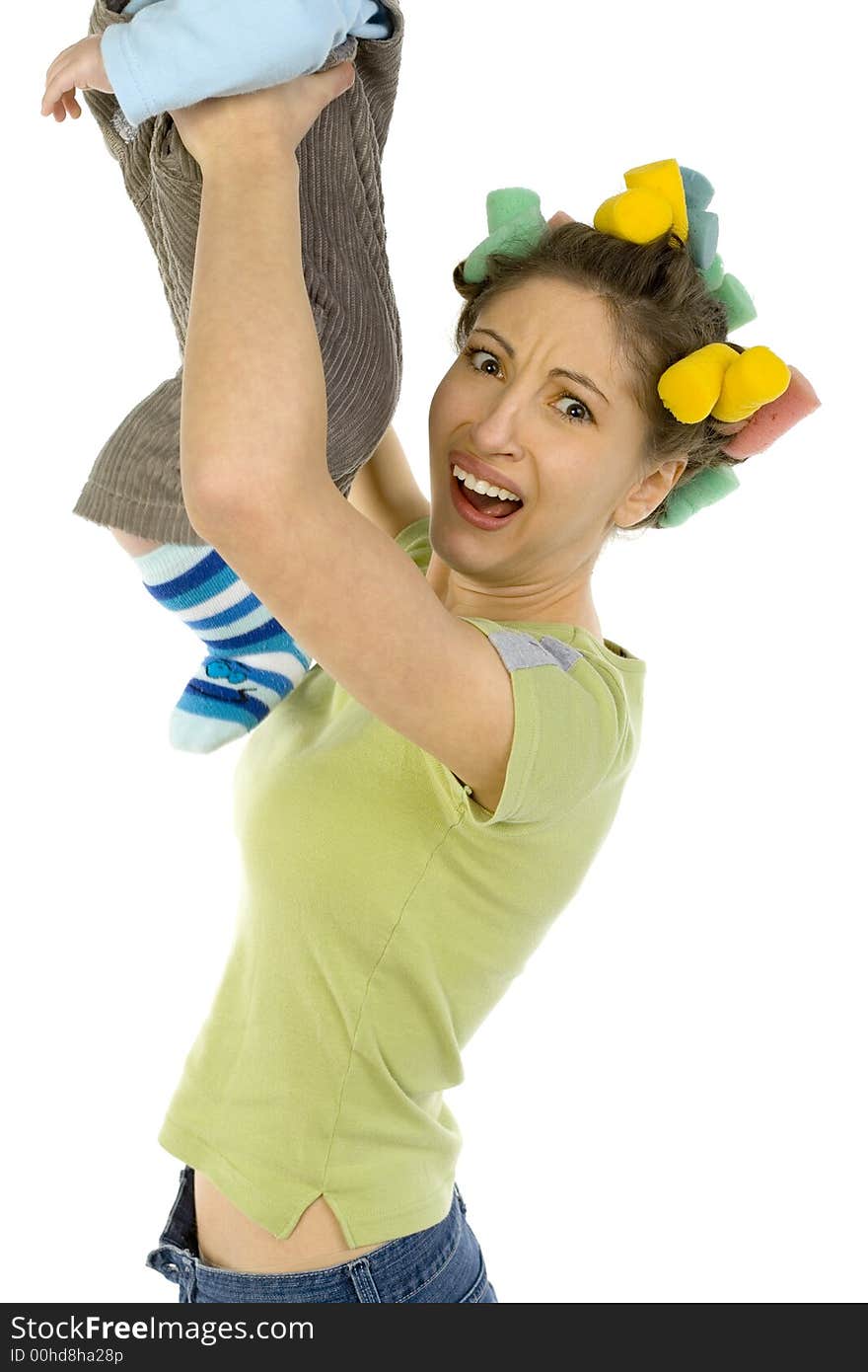 Young woman holding up baby and smelling his nappy. Showing on her face aversion. Looking at camera, white background. Young woman holding up baby and smelling his nappy. Showing on her face aversion. Looking at camera, white background