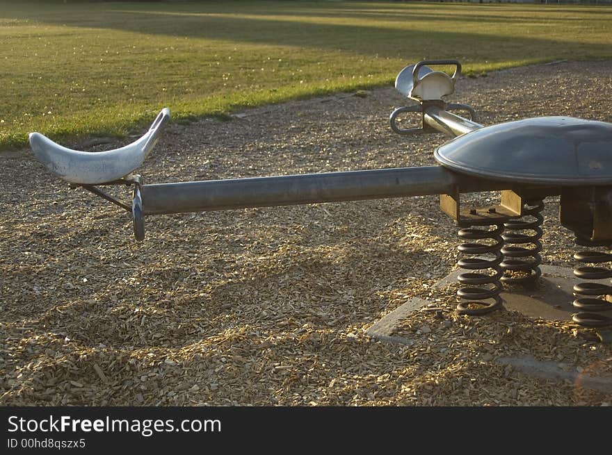 A seesaw in an empty playground just before sunset. A seesaw in an empty playground just before sunset.