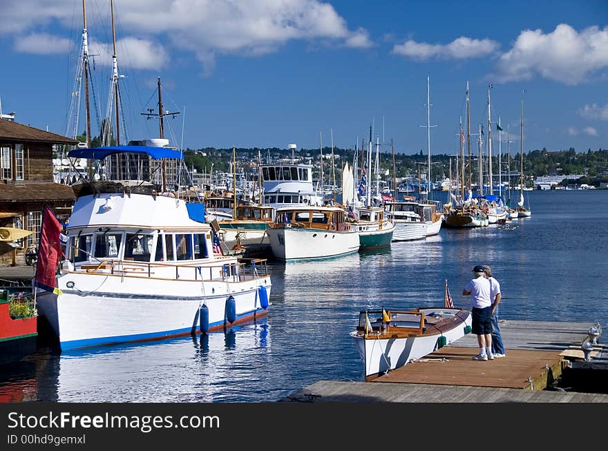 Two guys standing on the dock next to a classic wood boat at the marina. Two guys standing on the dock next to a classic wood boat at the marina