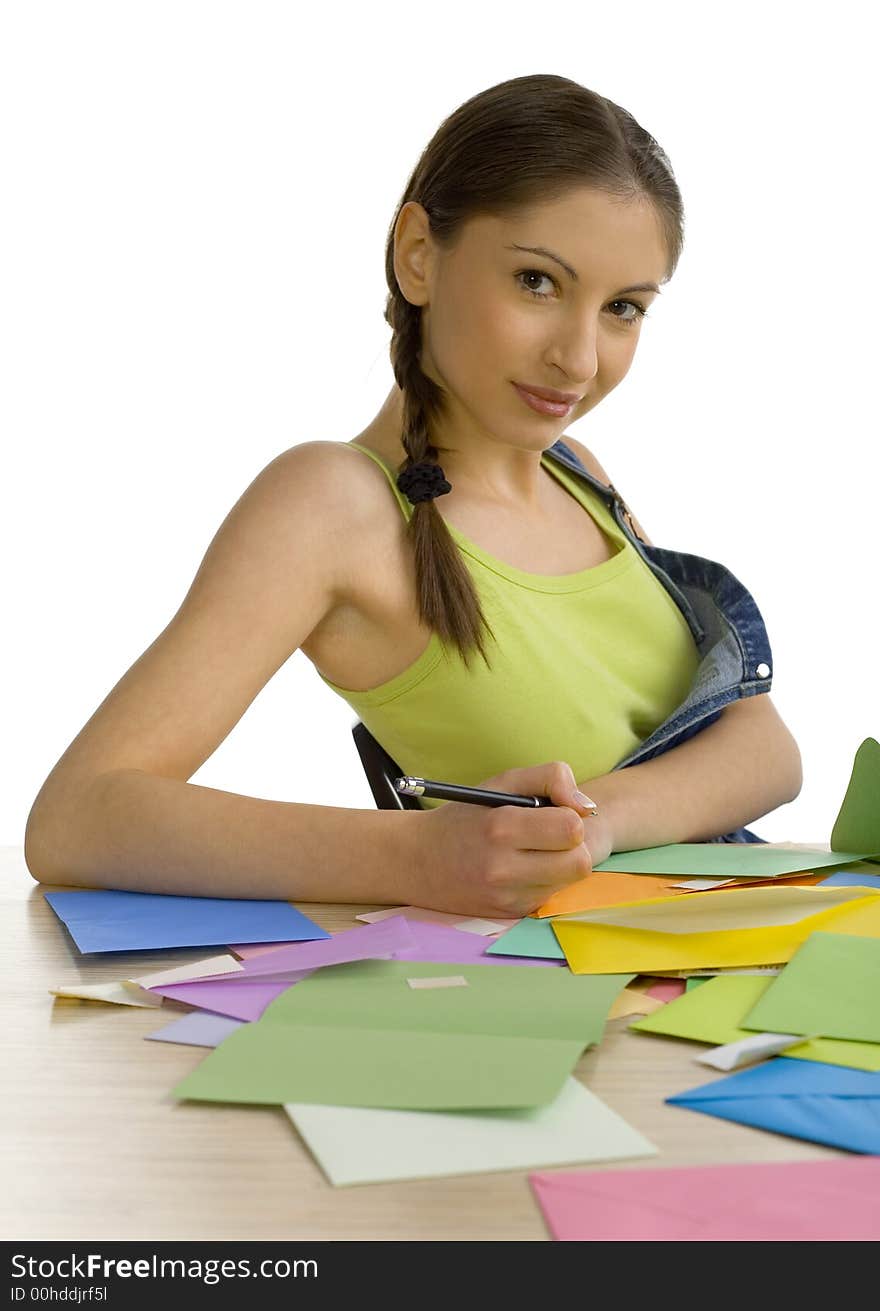 Young, beautiful woman sitting, smiling  and writing a letter. Looking at camera, front view. White background. Young, beautiful woman sitting, smiling  and writing a letter. Looking at camera, front view. White background