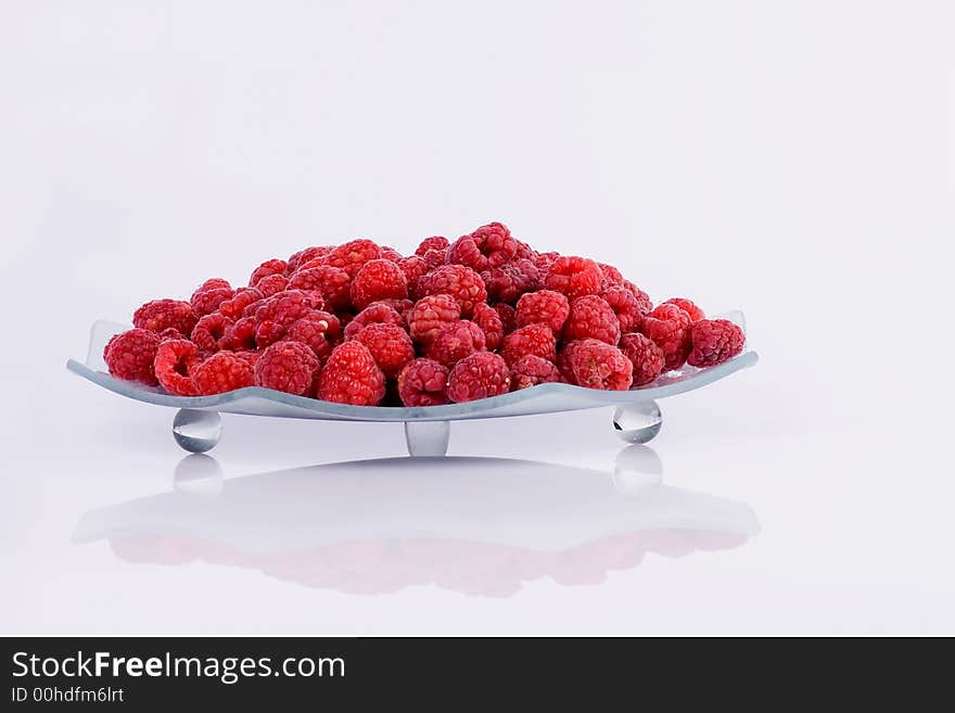 Raspberries on a glass plate on the  white  background