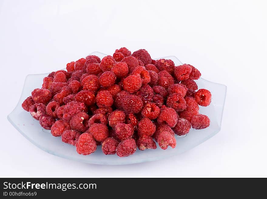 Raspberries on a glass plate on the  white  background