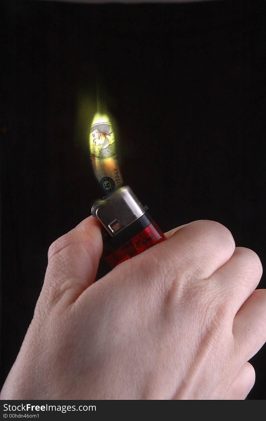 A cigarette lighter burns with a flame that resembles a dollar bill. Black background. A cigarette lighter burns with a flame that resembles a dollar bill. Black background.