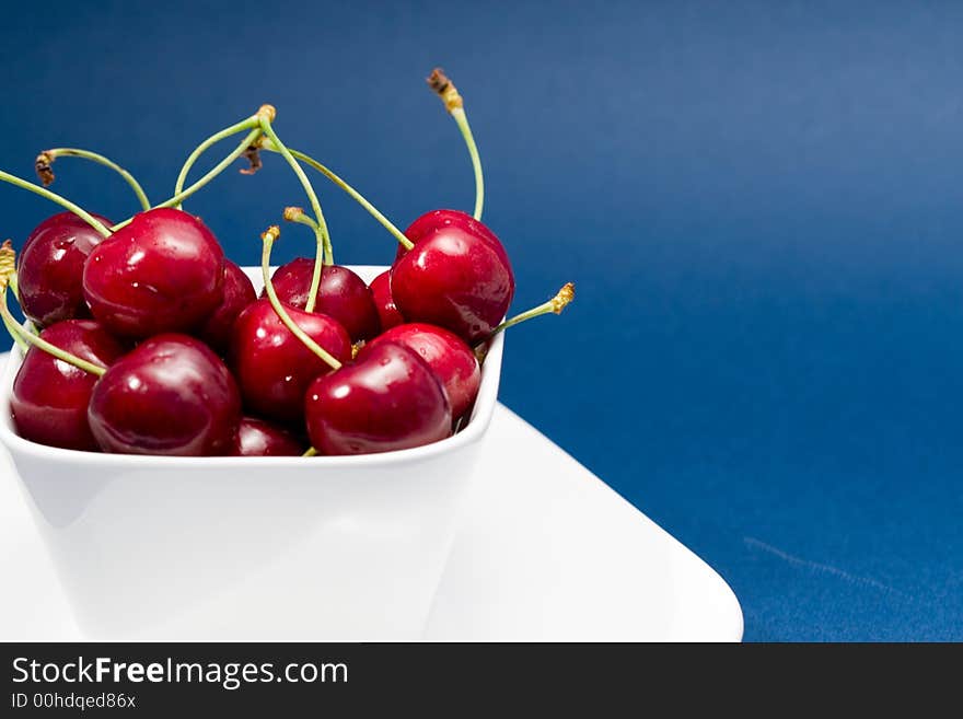 Multiple moist red cherries in a white bowl. Multiple moist red cherries in a white bowl