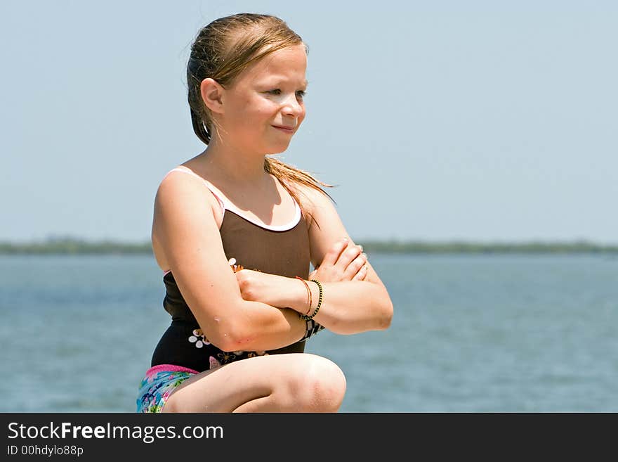 Young girl at waters edge portrait looking away. Shallow DOF with water and sky background