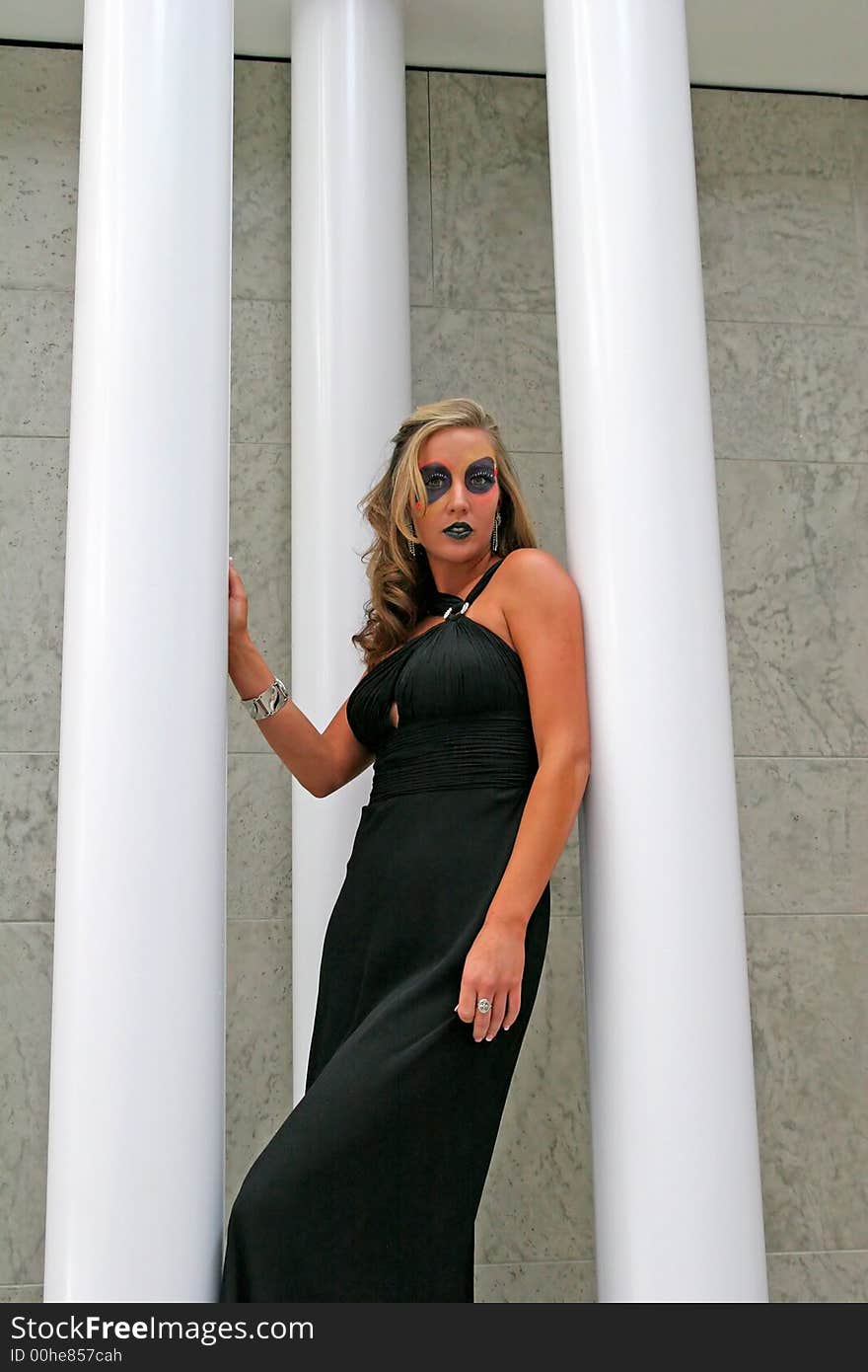 A fashion makeup model full length against white columns. A fashion makeup model full length against white columns