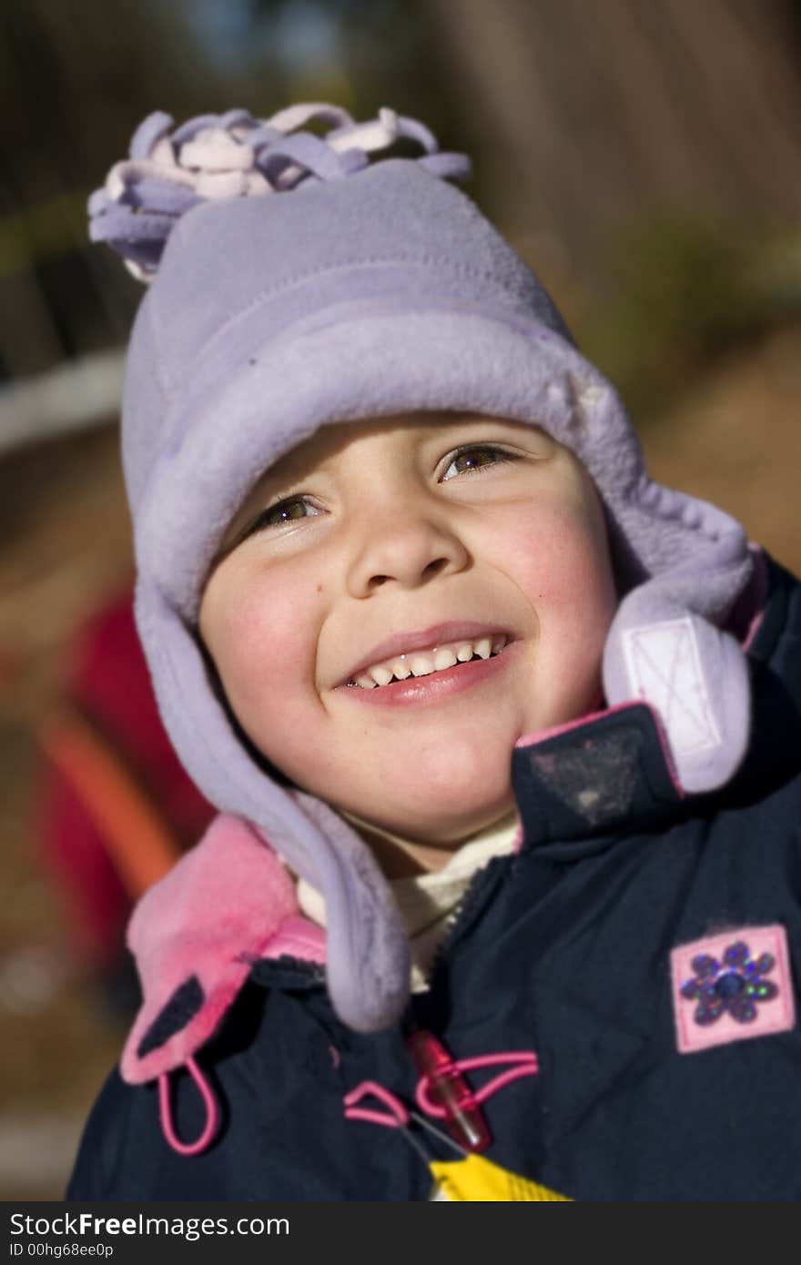 A little girl outside wearing a big coat and hat, smiling at the sun. A little girl outside wearing a big coat and hat, smiling at the sun.