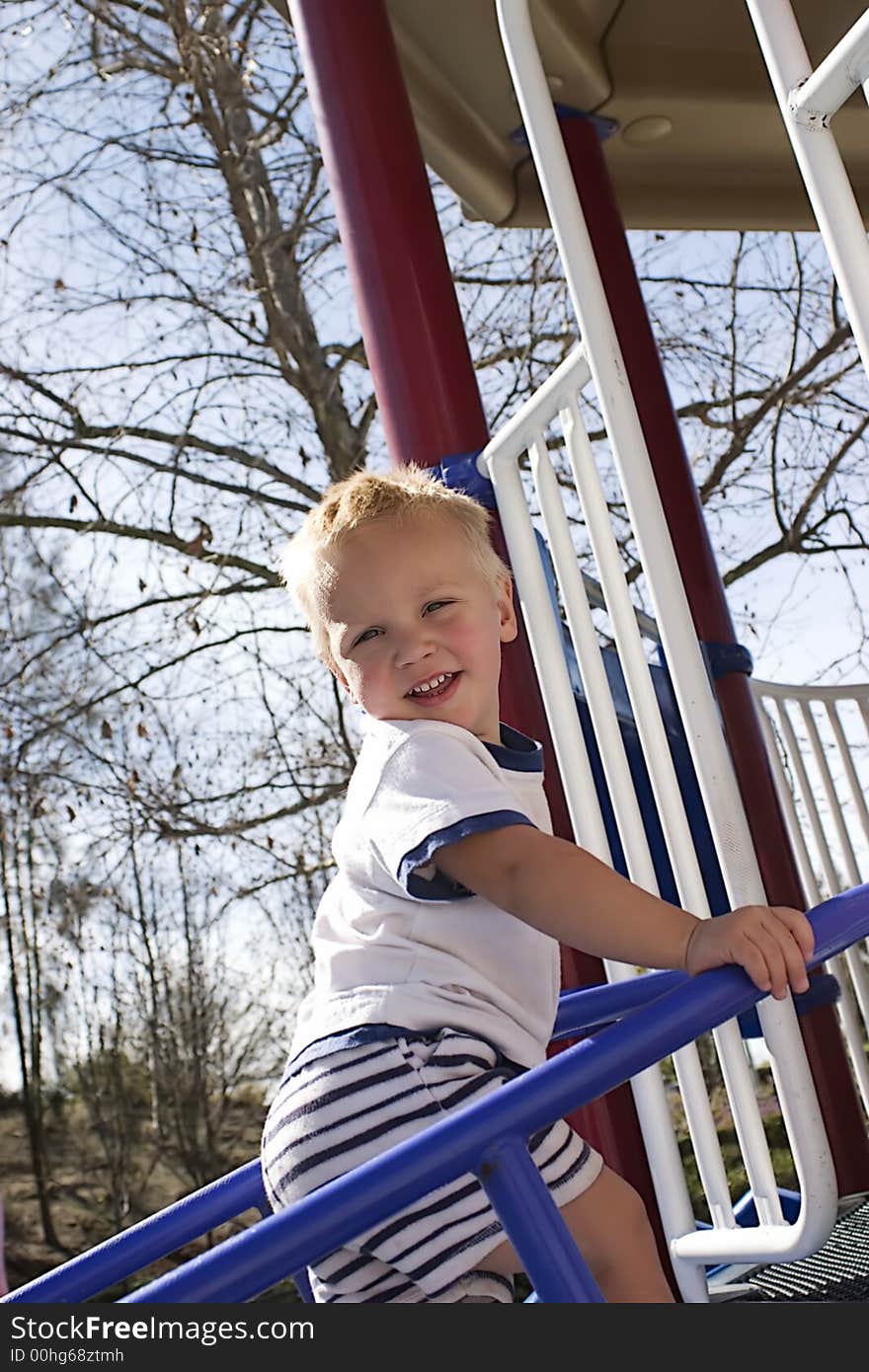 A small blond baby boy is outside climbing a stair. A small blond baby boy is outside climbing a stair.