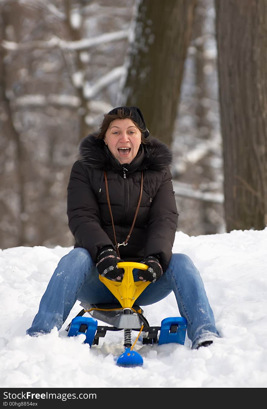 Excited woman, sliding downhill on a sledge.