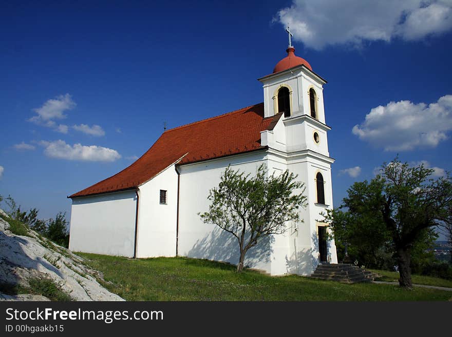 A white chapel with an almond trees and white rocks