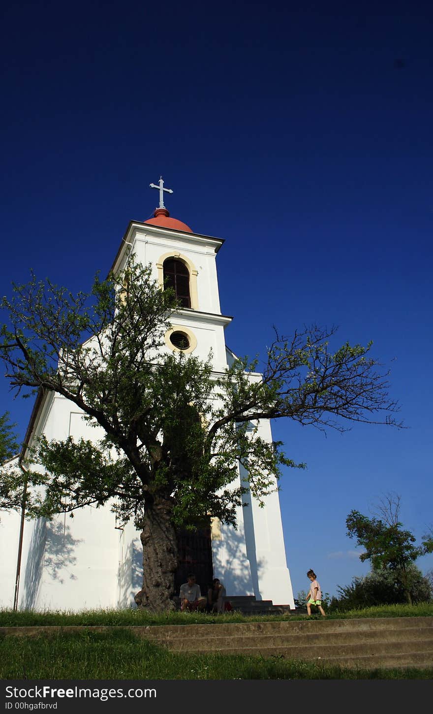 A white chapel with an almond trees and a girl walking