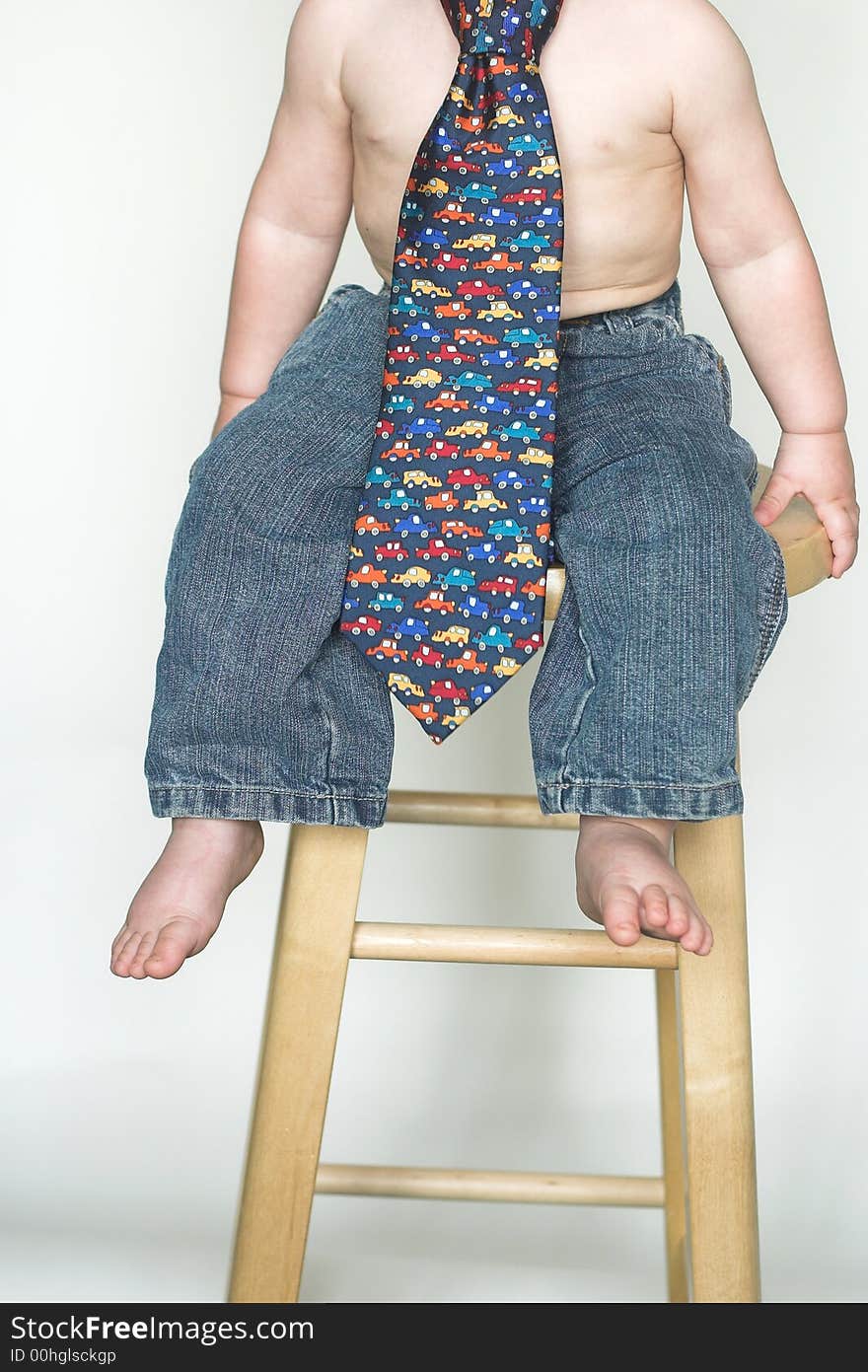 Image of cute toddler, only visible from the neck down, wearing jeans and a tie. Image of cute toddler, only visible from the neck down, wearing jeans and a tie