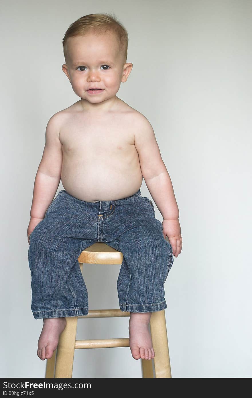 Image of a cute, happy toddler sitting on a stool. Image of a cute, happy toddler sitting on a stool