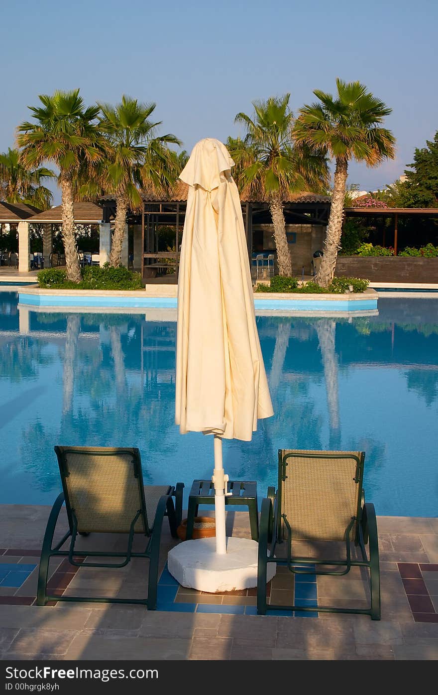 Sunshade and couch near of swimming pool in tropical resort