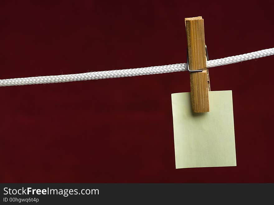 Yellow paper attach clothes-peg to rope on vinous background