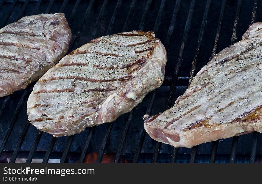 Grilling steaks on the grill nice cuts of meat close up shot shallow DOF. Grilling steaks on the grill nice cuts of meat close up shot shallow DOF