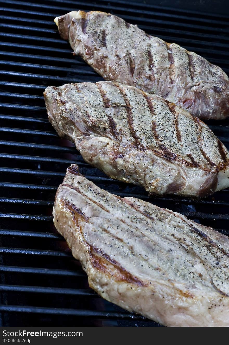 Grilling steaks on the grill nice cuts of meat close up shot shallow DOF. Grilling steaks on the grill nice cuts of meat close up shot shallow DOF