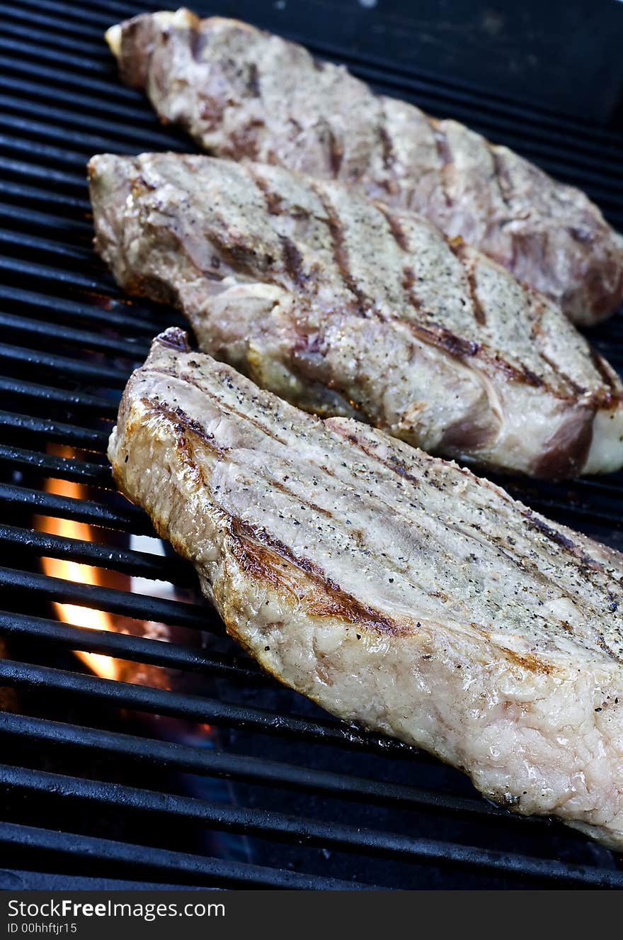 Grilling steaks on the grill nice cuts of meat close up shot shallow DOF. Grilling steaks on the grill nice cuts of meat close up shot shallow DOF