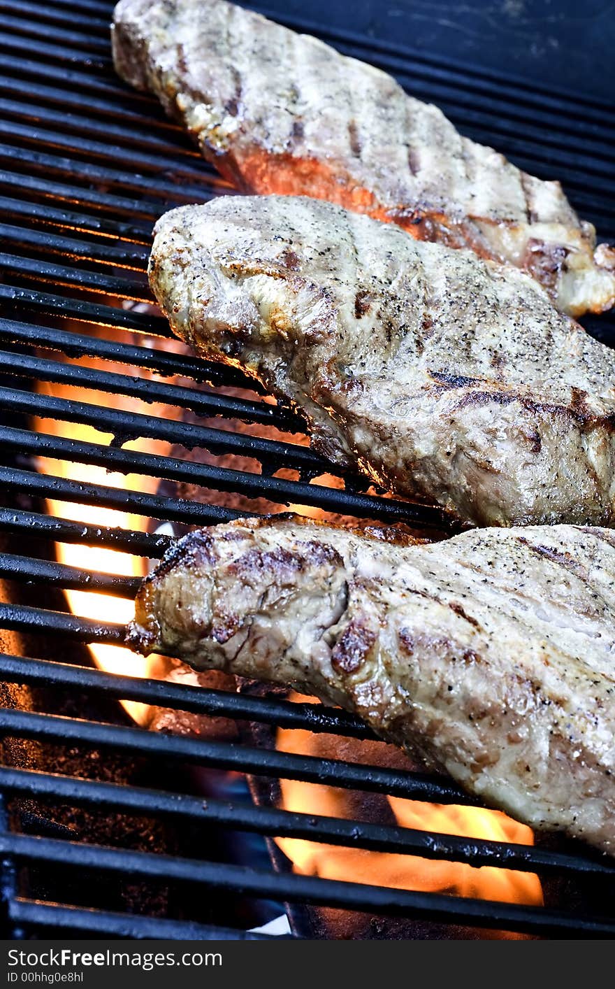 Grilling steaks on the grill nice cuts of meat close up shot shallow DOF. Grilling steaks on the grill nice cuts of meat close up shot shallow DOF