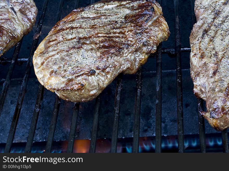 Grilling steaks on the grill nice cuts of meat close up shot shallow DOF. Grilling steaks on the grill nice cuts of meat close up shot shallow DOF