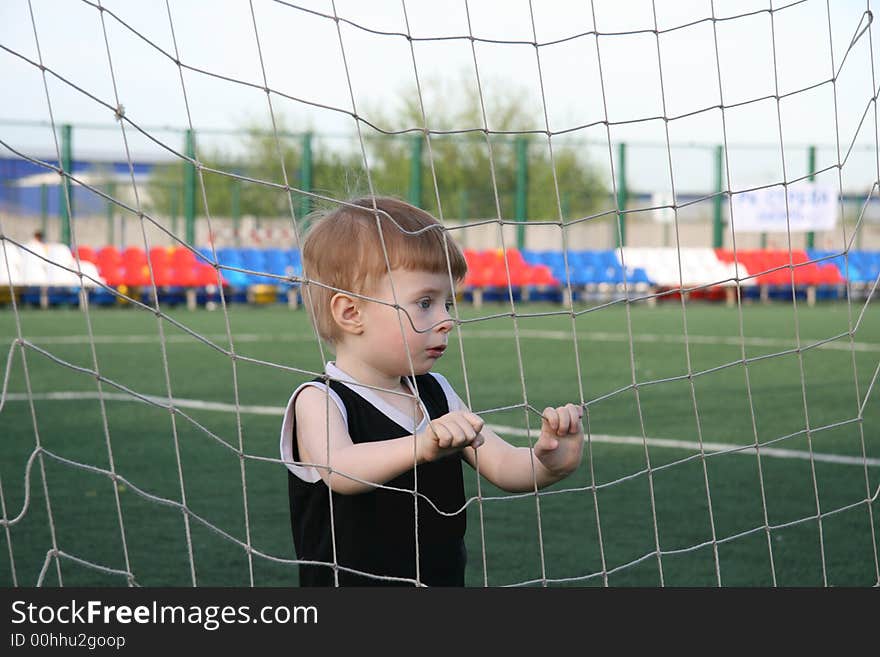 The boy in a grid of a football gate before the beginning of game. The boy in a grid of a football gate before the beginning of game