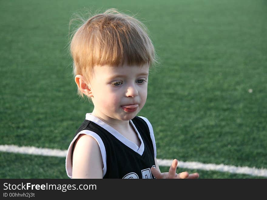 The fair-haired boy in the empty stadium, covered by the evening sun