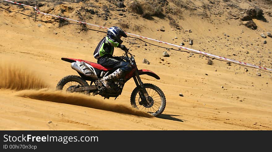 The sportsman on a motorcycle overcomes abrupt turn on a sandy line. The sportsman on a motorcycle overcomes abrupt turn on a sandy line