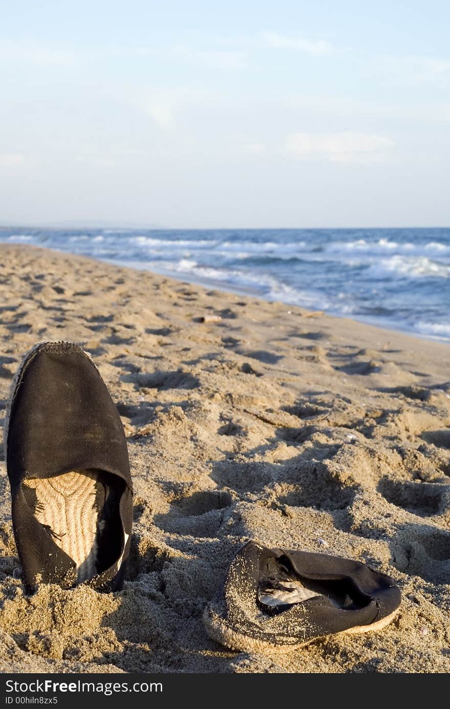 Stylish beach shoes photographed on the sand at sunset. Composition leaves a lot of space for typing. Stylish beach shoes photographed on the sand at sunset. Composition leaves a lot of space for typing