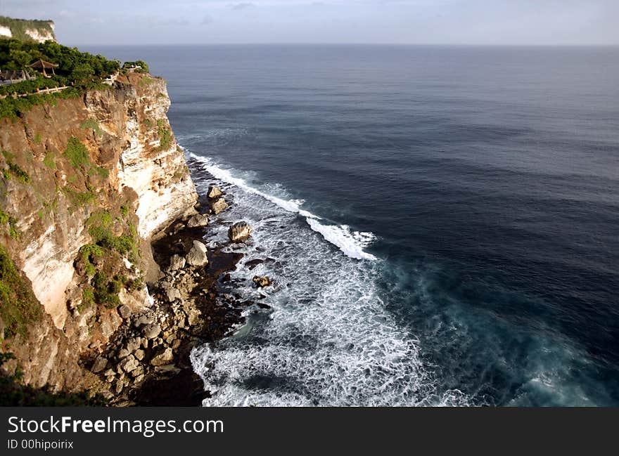 A steep cliff, water and sea.