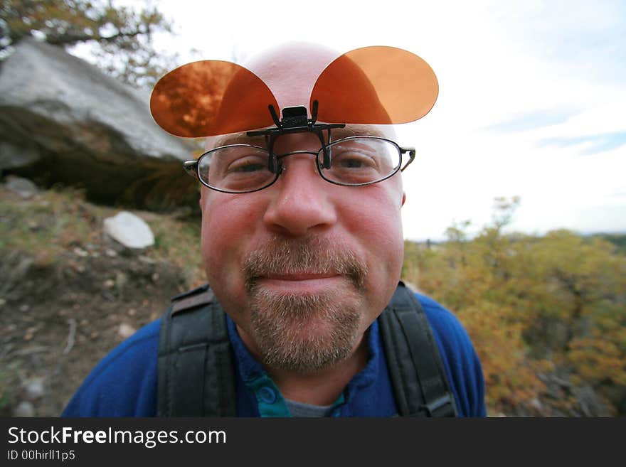 Wide angle egg head hiker upclose with flip shades for his glasses. Wide angle egg head hiker upclose with flip shades for his glasses