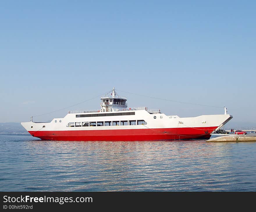 Red ferry boat docked unloading passengers and cars