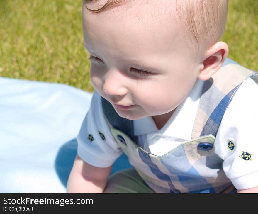 A very cute little infant sitting outside. A very cute little infant sitting outside