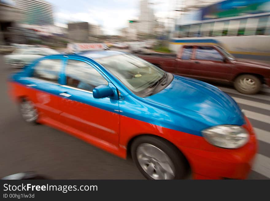 Speeding taxi in downtown traffic driving by on a city street. Speeding taxi in downtown traffic driving by on a city street