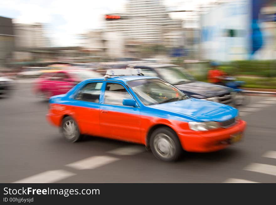 Speeding taxi in downtown traffic driving by on a city street. Speeding taxi in downtown traffic driving by on a city street