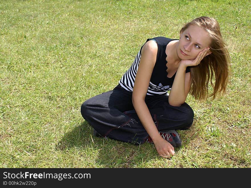 The girl sits on a grass. The girl sits on a grass