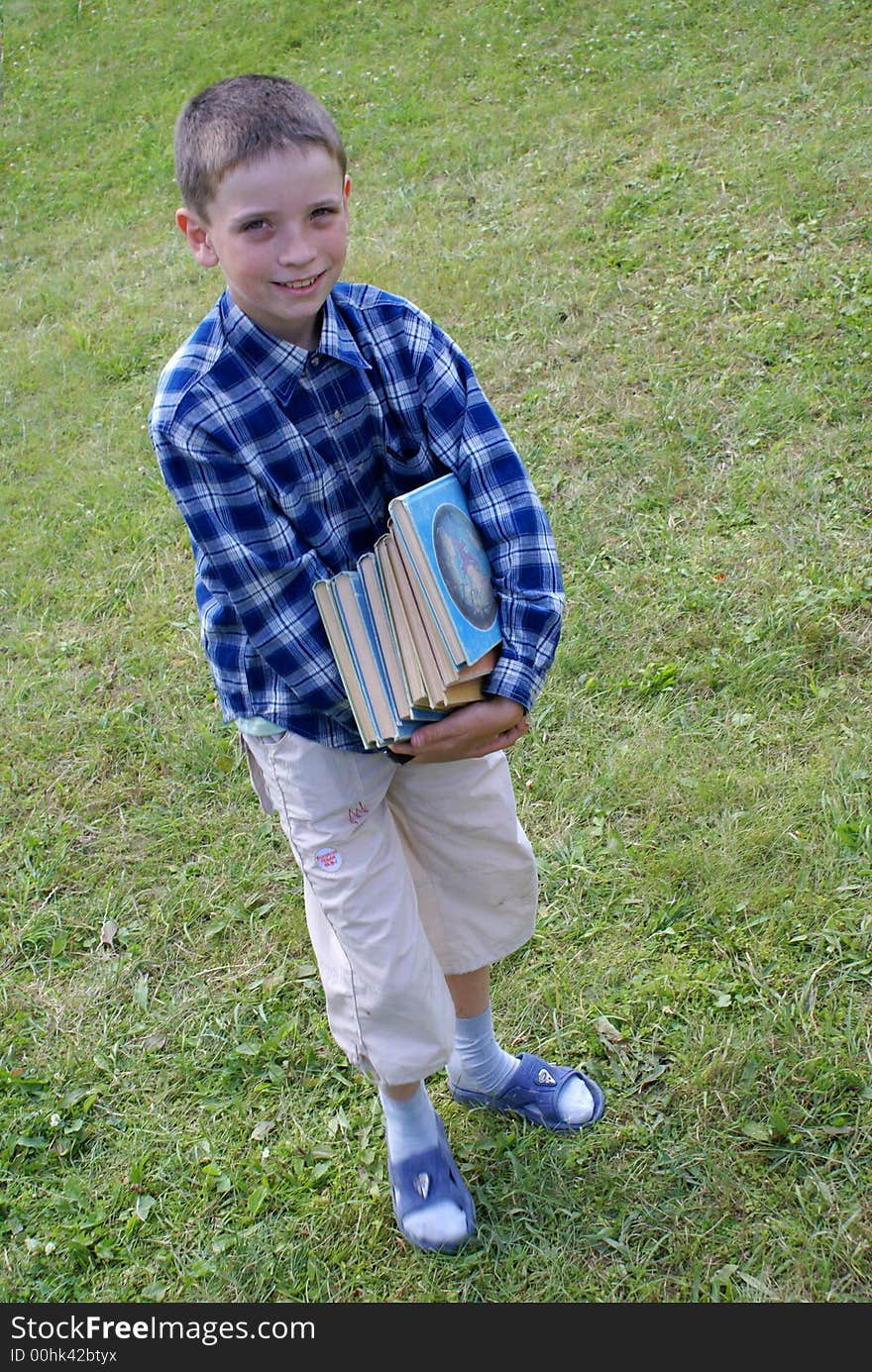 The boy drags a pile of heavy books. The boy drags a pile of heavy books