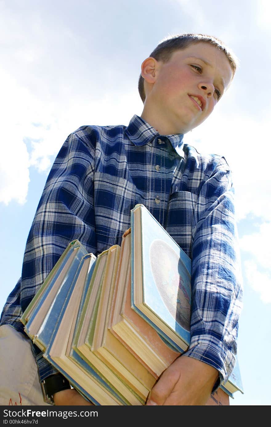 The boy drags a pile of heavy books. The boy drags a pile of heavy books